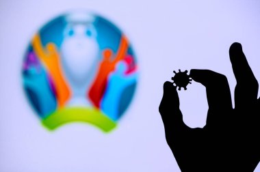 LONDON, UNITED KINGDOM - 25 Mayıs 2020: Eller silueti covid 19 virüsüne sahip, arka planda Euro 2020 yaz futbol turnuvasının logosu