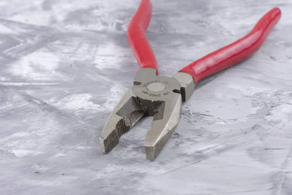 Gri arka planda kırmızı saplı pense, makro