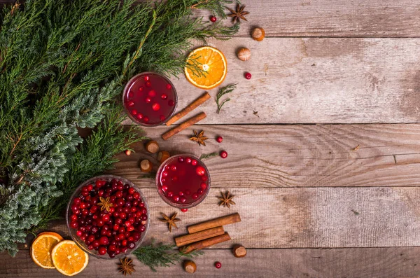 Christmas drinks. Hot winter drink with cranberries and cinnamon on a wooden table. Top view flat lay. Free space for your text.