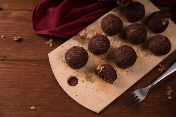 Cocoa balls, chocolate truffles cakes on board on wooden backgro