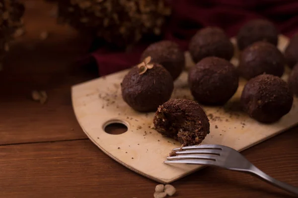 Cocoa balls, chocolate truffles cakes on board on wooden backgro
