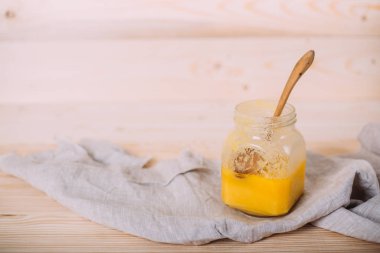 Ahşap arka planda bir kavanoz katı bal ve kumaş..