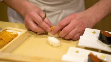 Şık bir restoranda Japon geleneksel yemeklerinden oluşan deniz kestaneli nigiri suşisini hazırlayan bir şefin yakın çekimi.