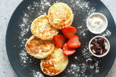 Çilekli peynirli krep, ekşi krema ve vişne reçeli. Tabakta peynirli krep