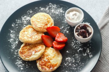 Çilekli peynirli krep, ekşi krema ve vişne reçeli. Tabakta peynirli krep