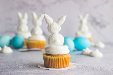 Güzel paskalya kompozisyonu. Mavi paskalya yumurtaları, paskalya tavşanları ve kuru üzümlü havuçlu kekler.
