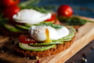 Haşlanmış yumurta, domates, avokado, baharat ve bitkilerle tost. Masada nefis bir kahvaltı