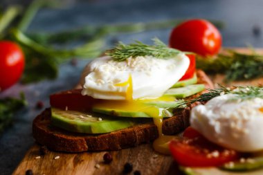 Haşlanmış yumurta, domates, avokado, baharat ve bitkilerle tost. Masada nefis bir kahvaltı