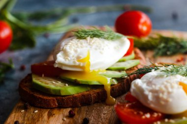 Haşlanmış yumurta, domates, avokado, baharat ve bitkilerle tost. Masada nefis bir kahvaltı