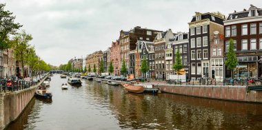 Amsterdam 'da klasik bir su kanalı, Hollanda şehir binaları üzerindeki köprüden görünüyor..