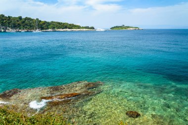 Gaios, şeffaf sakin deniz, kıyıdan küçük bir adaya manzara.
