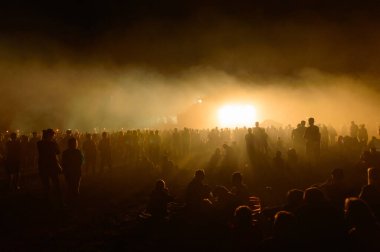 İnsanların siluetleri, herkes sisin parlak uzak bir noktasına bakıyor..