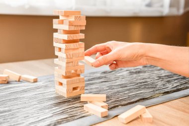 Jenga tahta bloklar, atari partisi oyunu. Ev koşullarında eğlence, istiflenmiş kule yıkılana kadar bloğu kaldırmaktan ibarettir. Oyun odadaki masada oynanır..