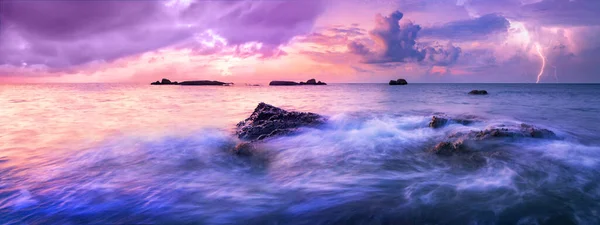 Colorful calm sea during sunset. A storm is approaching over the horizon. Colorful dark clouds in the air, electric discharges herald the coming storm.