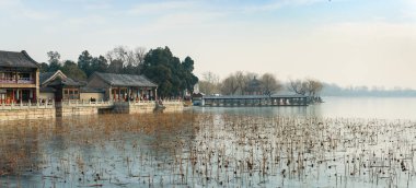 İmparatorluk bahçesinden, donmuş Kunming Gölü kıyısındaki Çin binalarına ve kuru nilüfer çiçeklerine bakın..