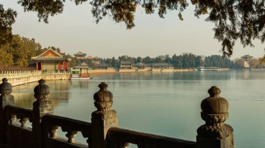 İmparatorluk bahçesindeki ara sokaktan, donmuş Kunming gölünün kıyısındaki Çin binalarına bak..