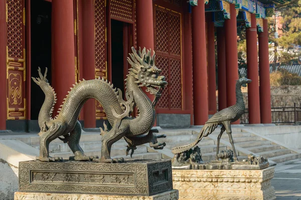 Klasik Çin heykelleri renkli eski bir binanın önünde duruyor..