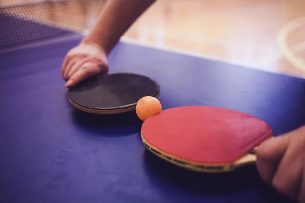 Blue table tennis or ping pong. Close up ping pong net and line. Two table tennis or ping pong rackets or paddles and ball on a blue table with net background