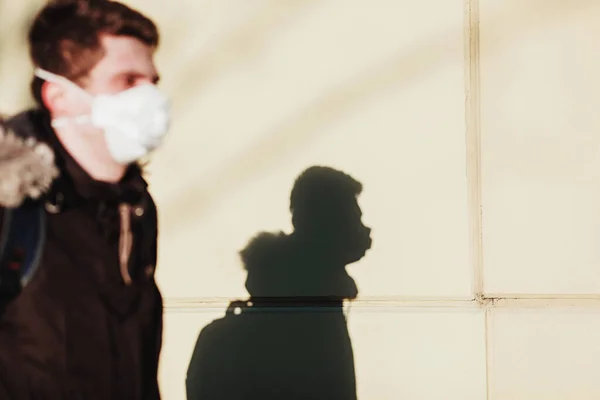 Man with mask to protect her from Corona virus. Corona virus pandemic. Young man with mask standing next to wall.