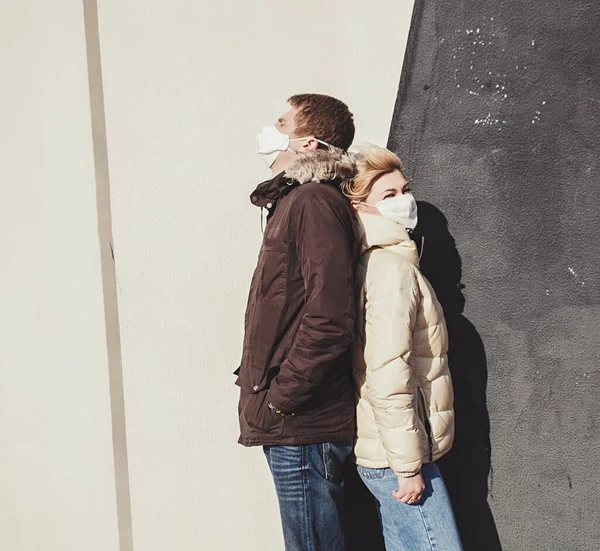 Woman and a man with masks near wall. Protection against Coronavirus COVID-19 (SARS-CoV-2) and other infectious diseases.