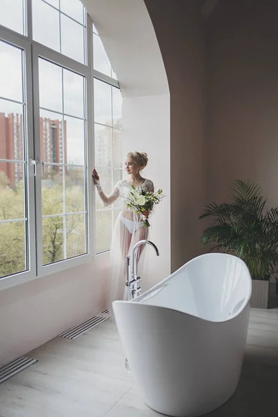 Perfect bride with hairstyle and wedding bouquet in hotel room