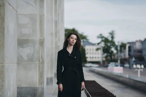 Stylish lady in elegant black coat walking on city