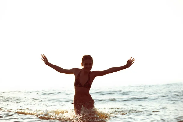 Silhouette of girl having fun in Baltic sea splashing waves — Stock Photo, Image