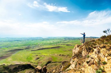 Rock cliff uzak el ile işaret üstünde genç adam