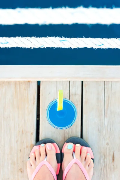 Fresh soft blue limonade drink close to cute female's feet — Stock Photo, Image