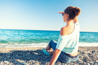 Genç güzel kız okyanus ufuk doğru çakıl beac üzerinde seyir