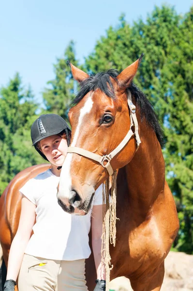 Junge Reiterin im Teenageralter mit ihrem braunen Pferd — Stockfoto