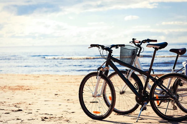 Dos bicicletas de pie en la arena de la playa en la costa del mar —  Fotos de Stock