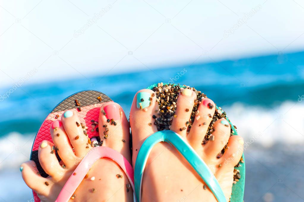 Summertime enjoyment! Feet on the beach. Blue ocean waves backgr