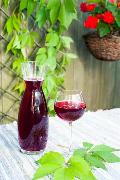 Copa y decantador con vino tinto casero en la mesa en el jardín — Foto de Stock