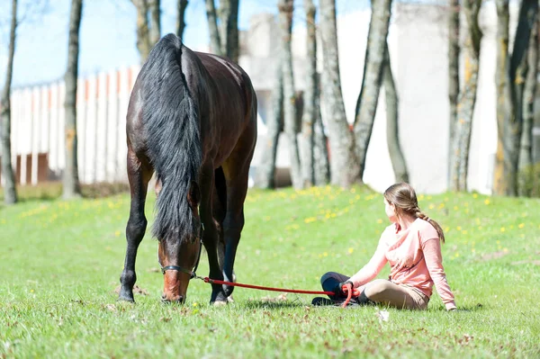 Joven adolescente propietario sentado cerca de su caballo favorito — Foto de Stock