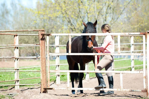 Jovem adolescente com seu cavalo marrom no curral — Fotografia de Stock