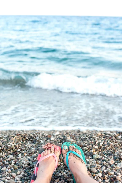 Feet in multicolored slippers on pebble beach. View from above — Stock Photo, Image