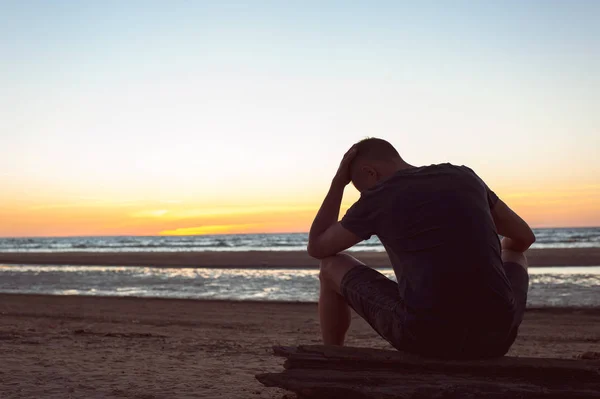 Zatíženy neviditelné starostí. Smutný osamělý muž sedí na pláži — Stock fotografie