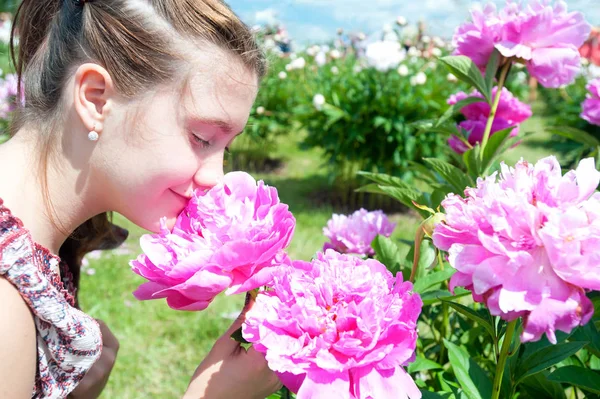 Hübsche Teenager-Mädchen riecht rosa blühende Pfingstrose Blumen in pa — Stockfoto