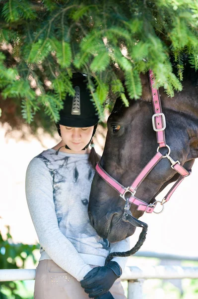 Junges Reitermädchen im Teenageralter steht neben ihrem braunen Pferd — Stockfoto