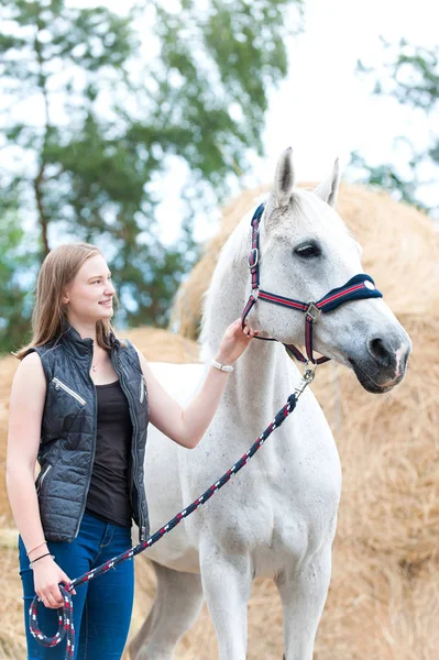 Mladá dospívající dívka majitel stojící vedle svého bílého koně — Stock fotografie