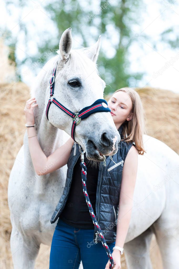 Portrait of young teenage blondy girl with white horse
