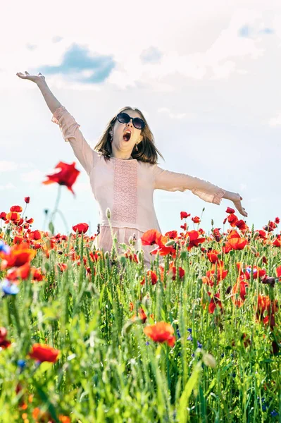 Carefree funny girl singing in summer poppy flowers field