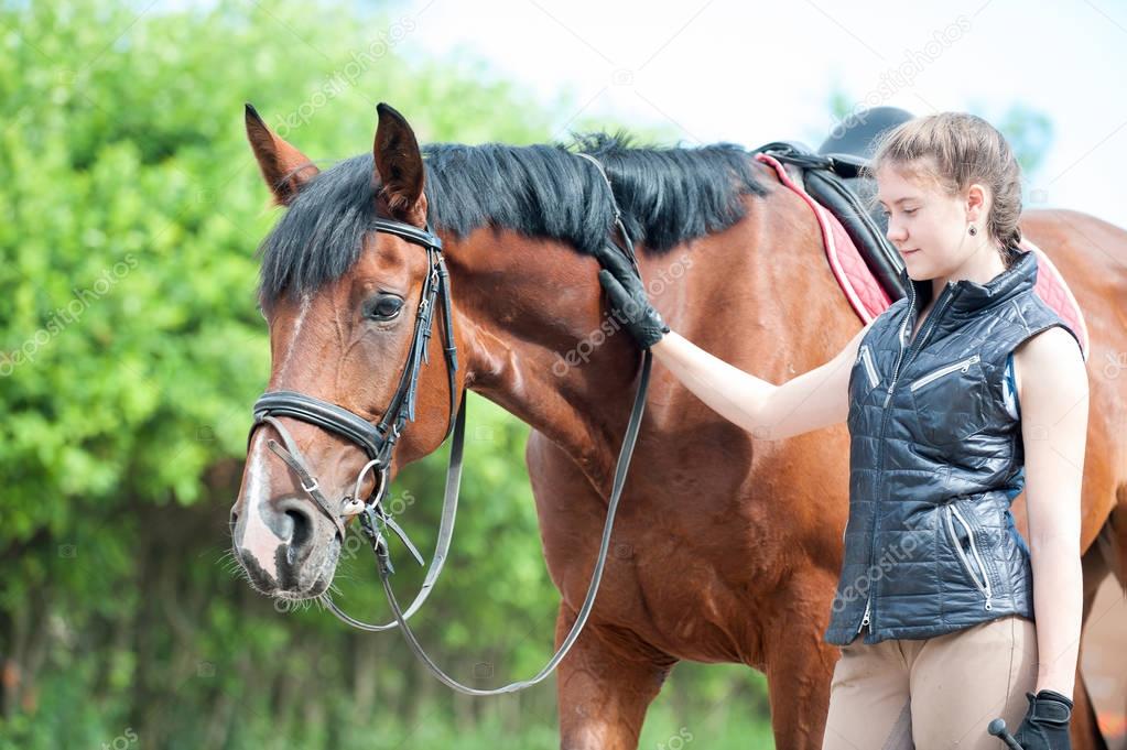 Young teenage girl tenderly looking at her favorite red horse