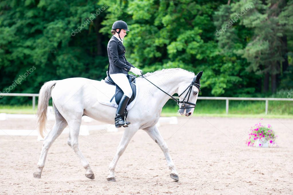 Teenage girl equestrian in dress uniform riding horseback on are