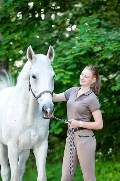 Bastante joven adolescente arañando el cuello del caballo blanco — Foto de Stock