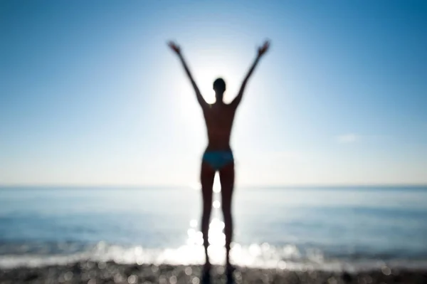 Girl silhouette standing on seaside with arms outstretched to su — Stock Photo, Image