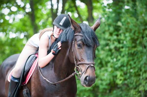 Mladí dospívající lady jezdecké všeobjímající její oblíbené frend hnědá — Stock fotografie