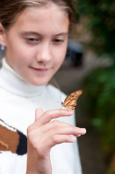 Schöner Schmetterling sitzt auf der Hand eines hübschen Mädchens — Stockfoto