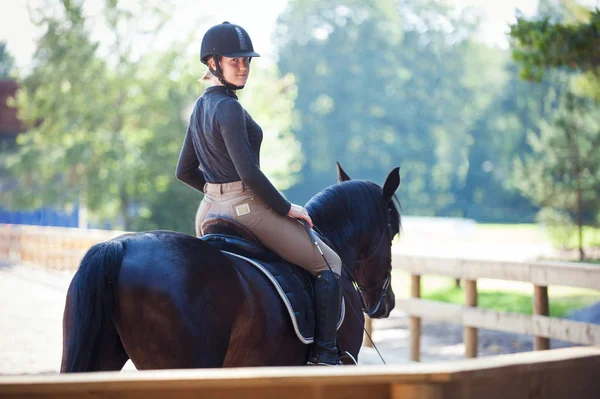 Joven chica bonita descansando después de montar a caballo de entrenamiento en la arena — Foto de Stock
